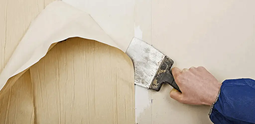 Handyman removing wallpaper with a scraper for wall preparation in Orlando, FL