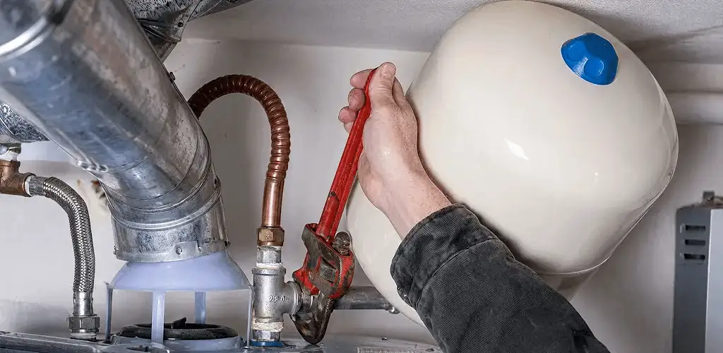 Water heater repair technician tightening plumbing connections near a tank unit in Orlando, FL